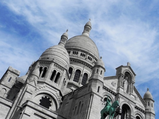 white and gray concrete dome building under blue sky during daytime in Basilique du Sacré-Cœur France