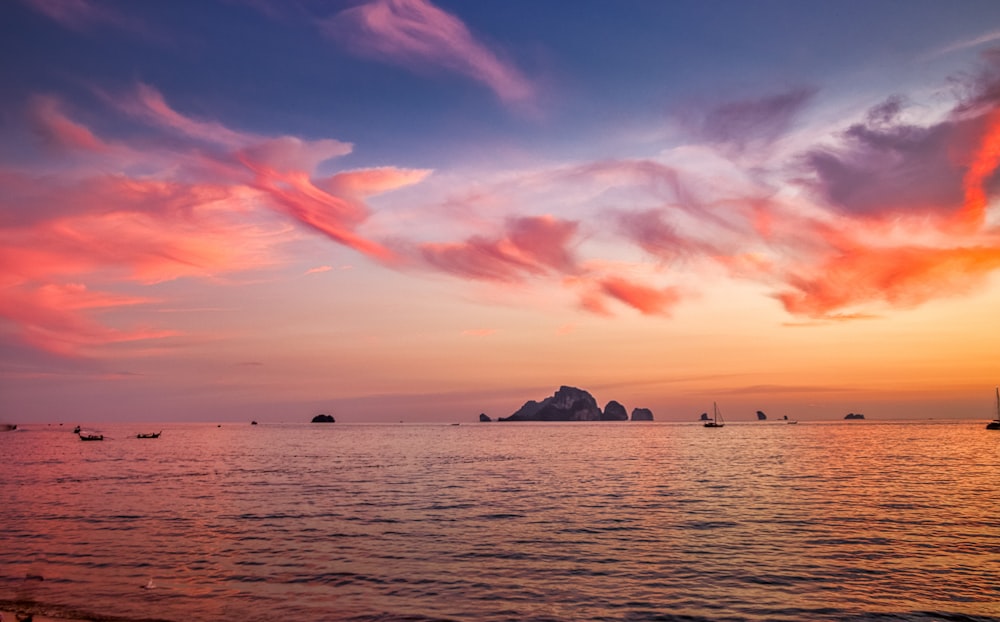 silhouette of mountain on body of water during sunset