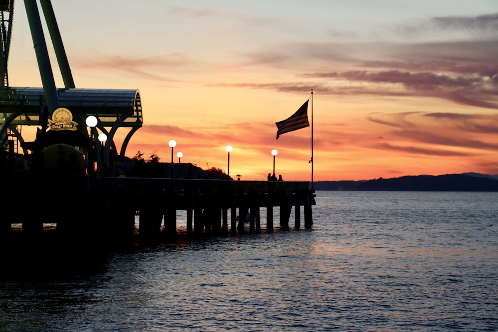 silhouette of people on wooden dock during sunset