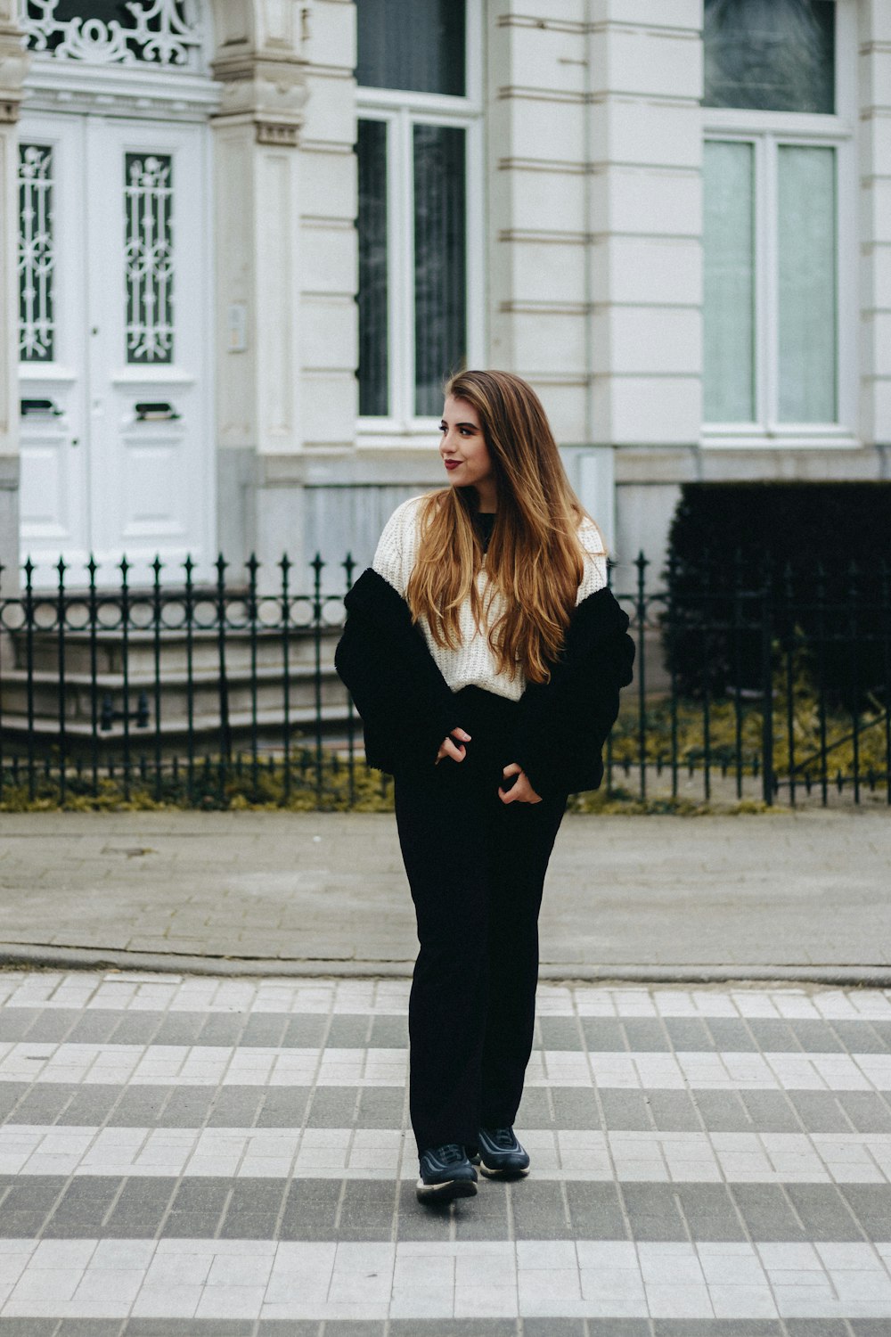 woman in black long sleeve shirt and black pants standing on sidewalk during daytime