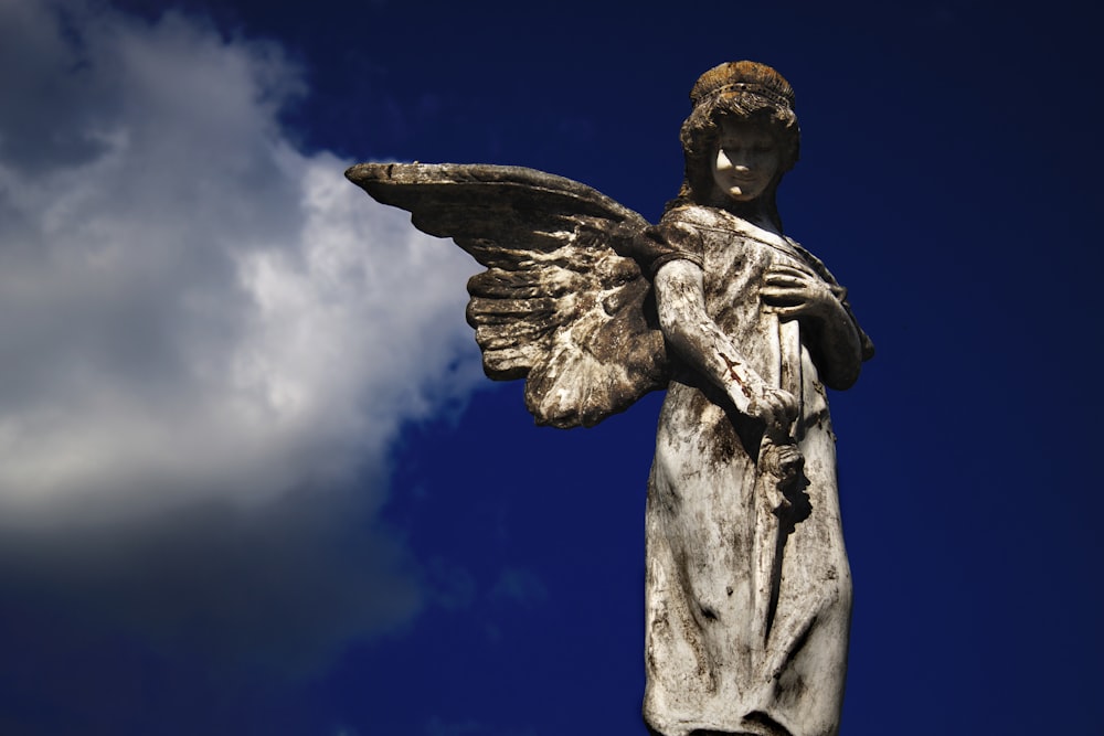 hombre sosteniendo estatua de libro bajo el cielo azul