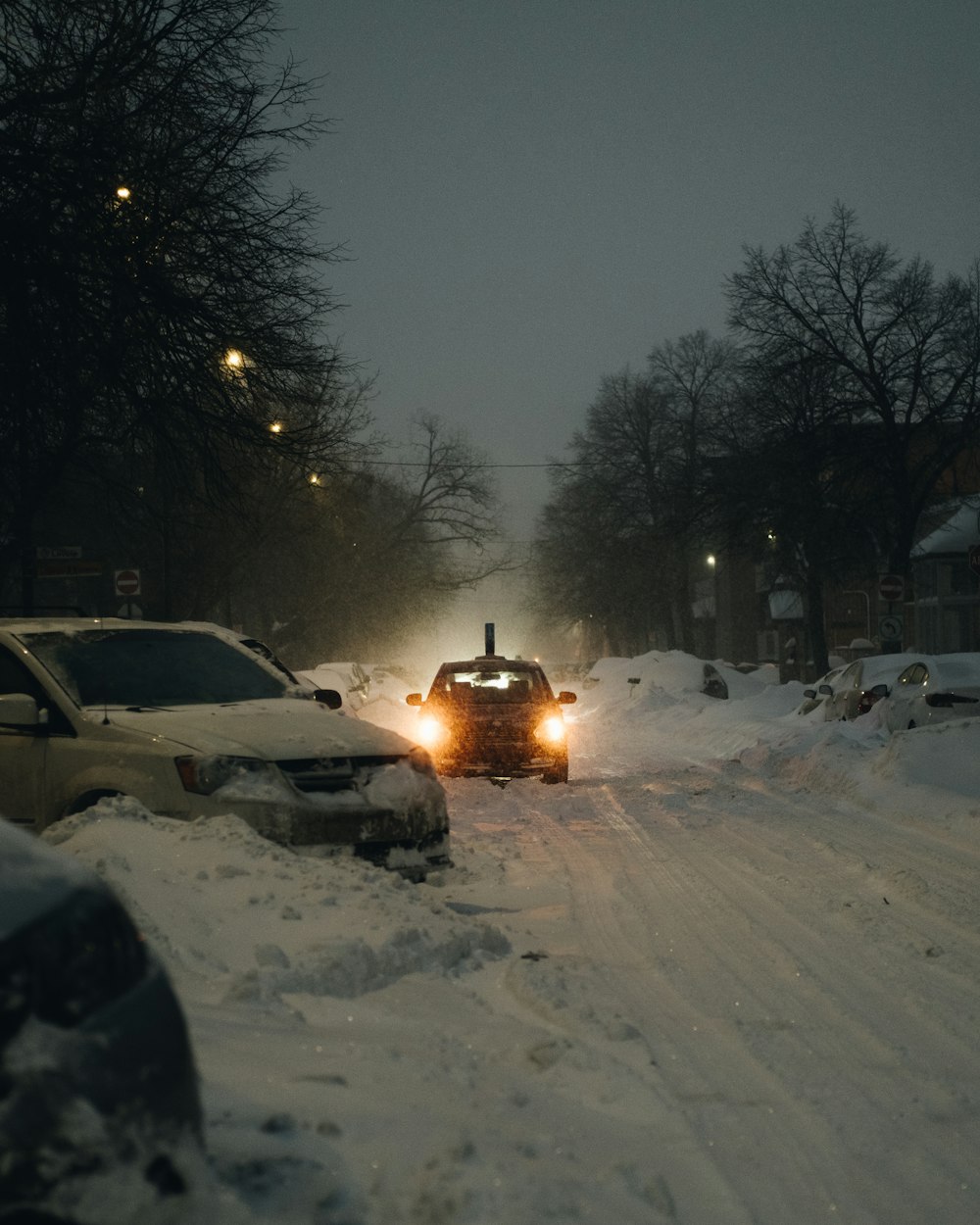 white car on snow covered road during night time