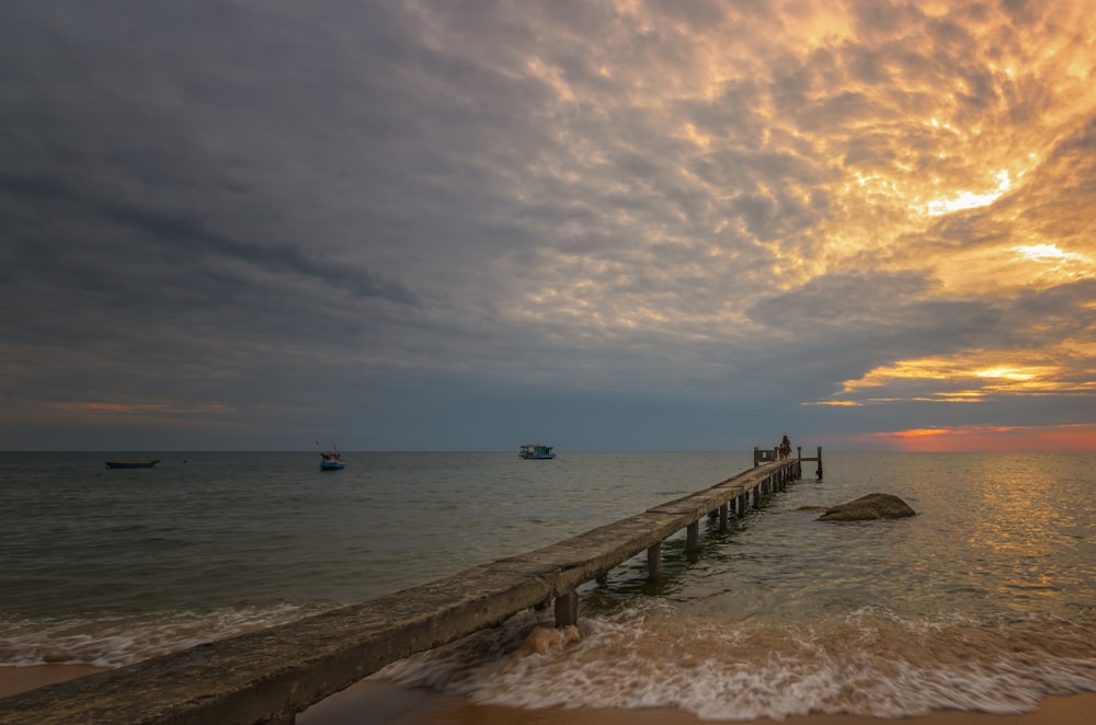 personnes sur le quai de plage au coucher du soleil