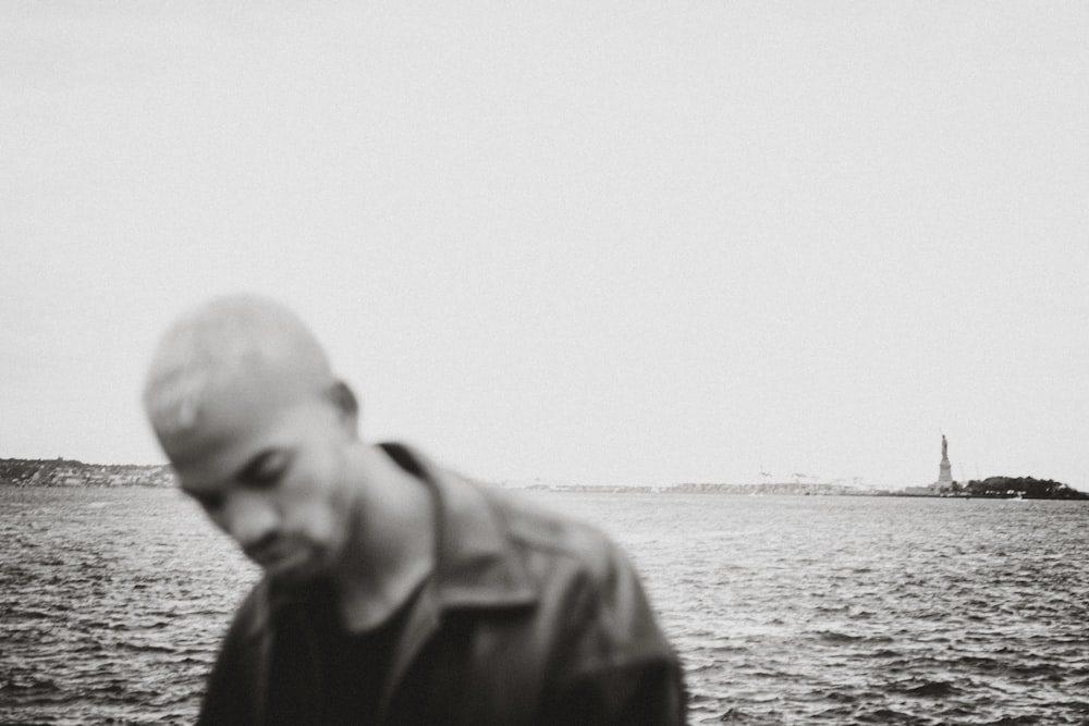 man in black jacket standing near body of water during daytime