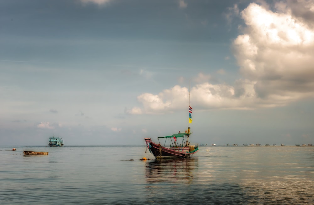 brown boat on sea under white clouds during daytime