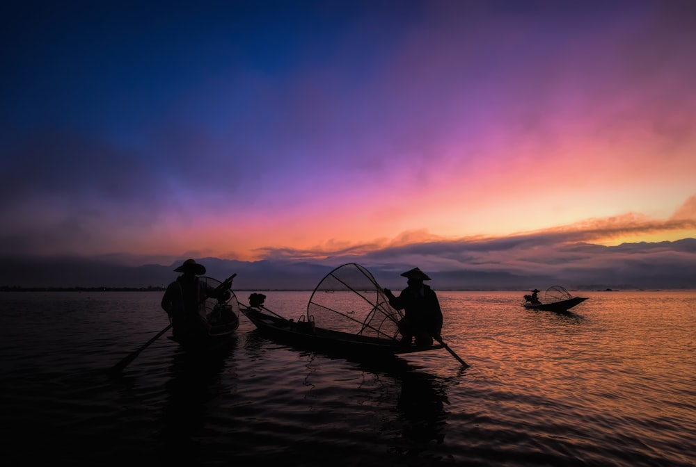 Silhouette von 2 Personen, die bei Sonnenuntergang auf dem Boot fahren