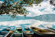 white and blue boat on lake near snow covered mountain during daytime