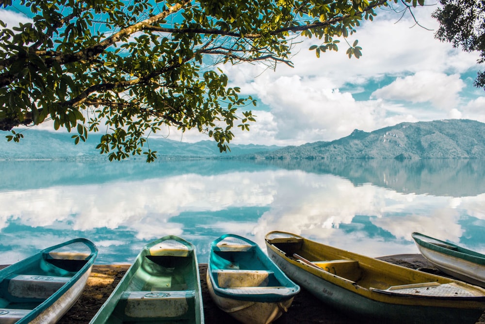 white and blue boat on lake near snow covered mountain during daytime