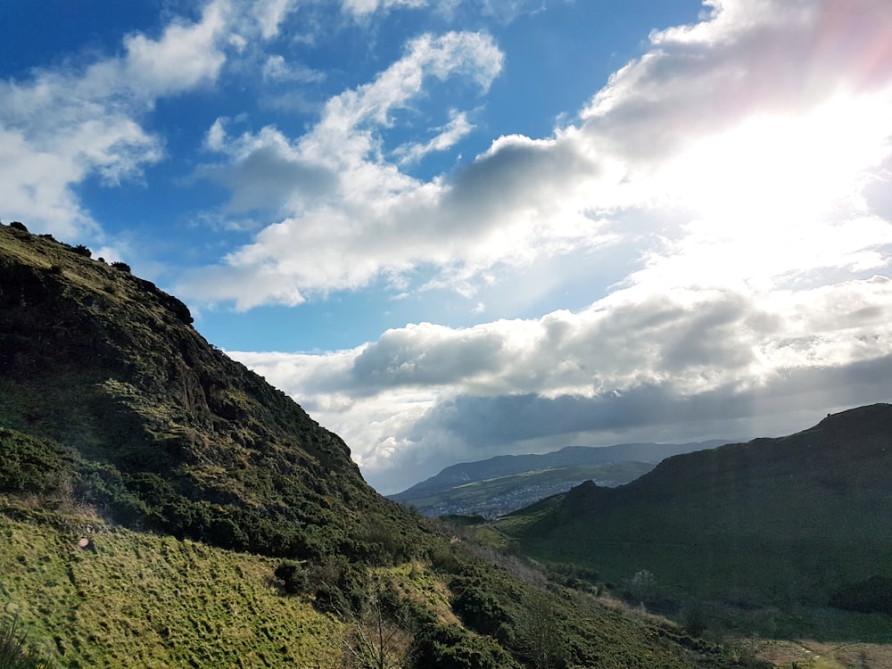 green mountains under white clouds and blue sky during daytime