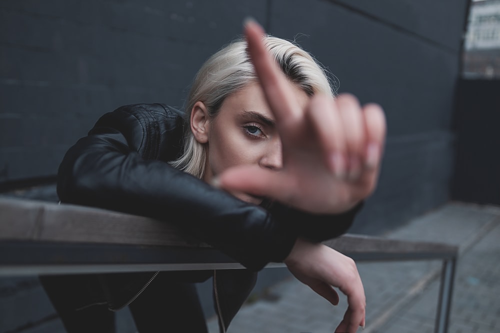 woman in black leather jacket leaning on black wooden table