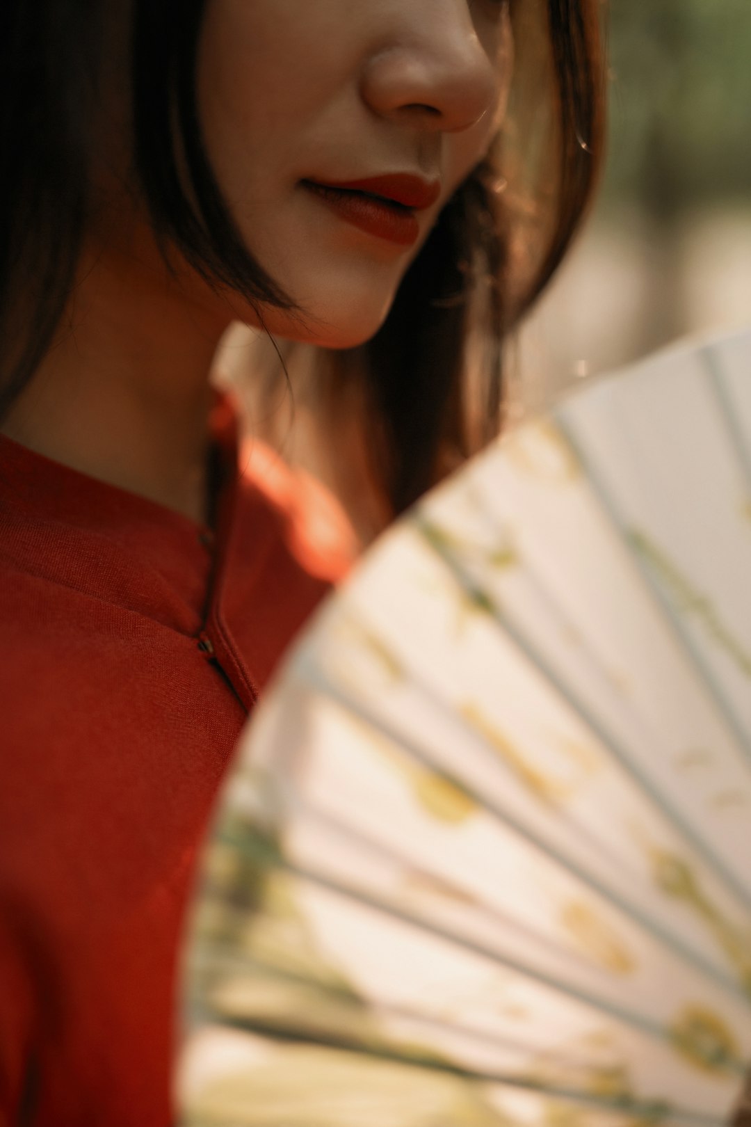 woman in red shirt holding white hand fan