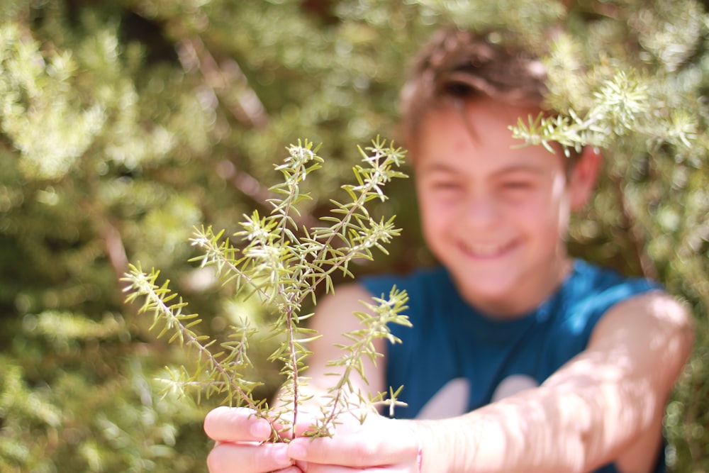 man in blue crew neck shirt holding green plant