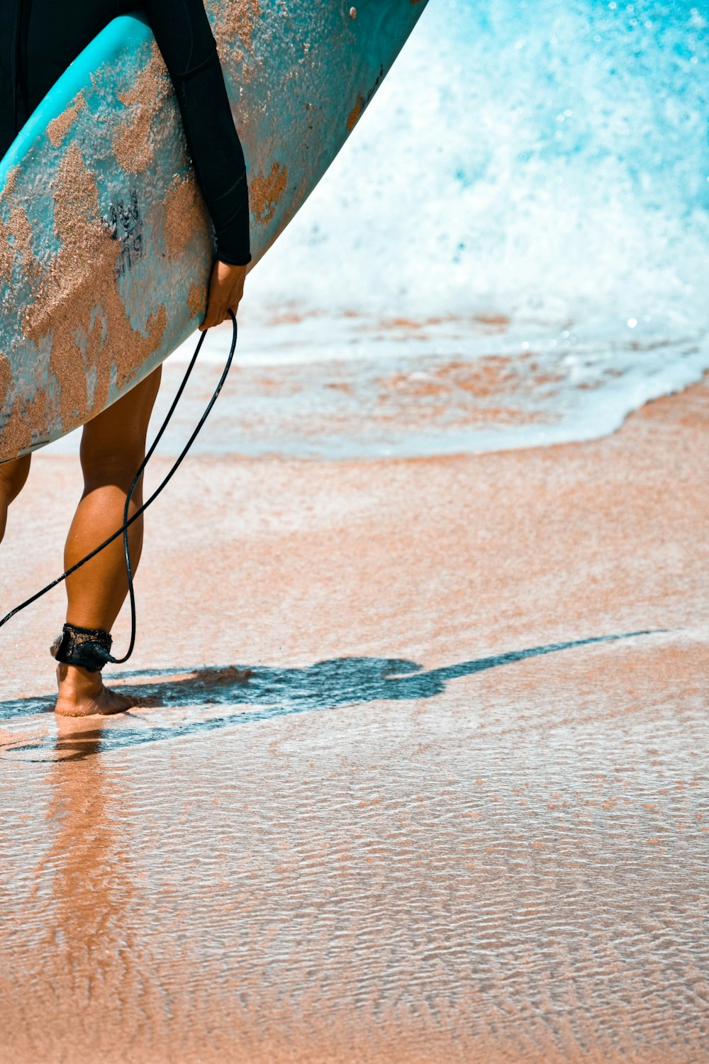 Person in schwarzen Ledersandalen, die tagsüber am Strandufer steht