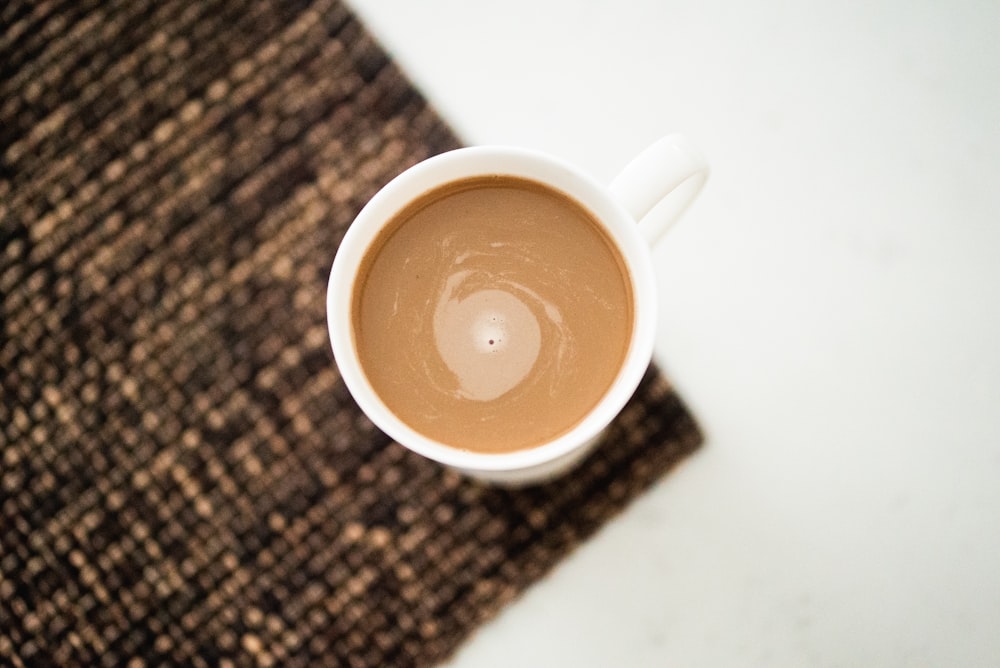 white ceramic mug on black and brown textile