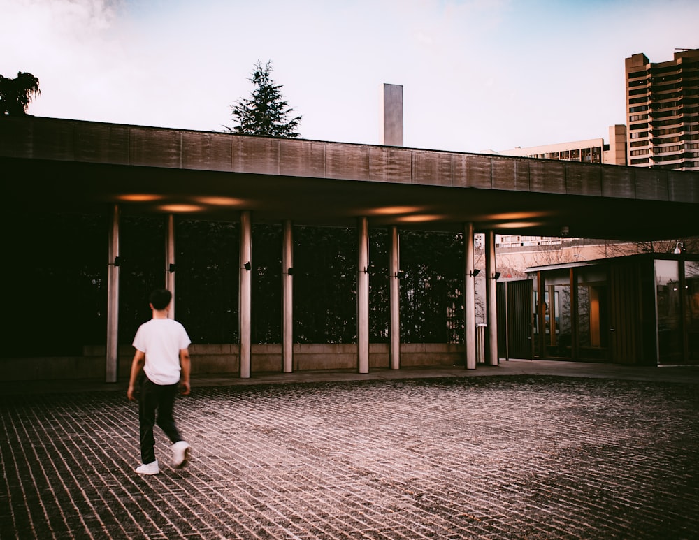 man in white long sleeve shirt and black pants walking on sidewalk during daytime