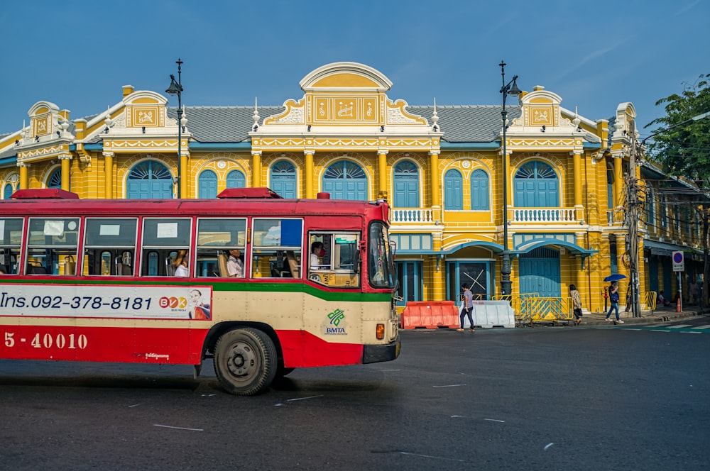 red and yellow bus on road near beige concrete building during daytime