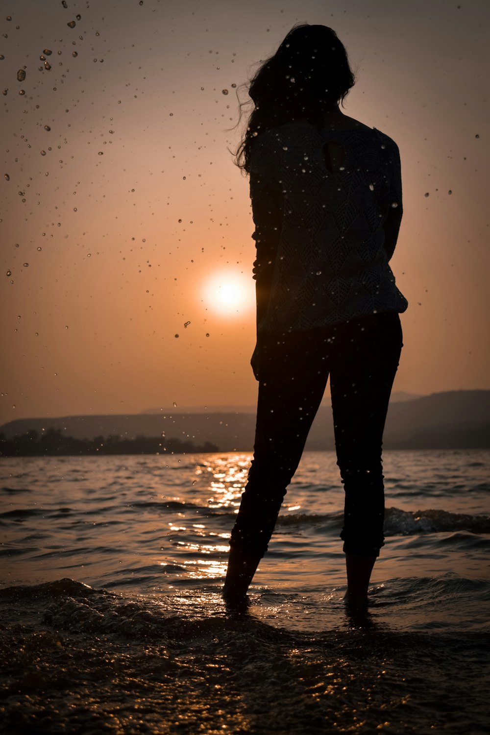 silhouette of woman standing on beach during sunset