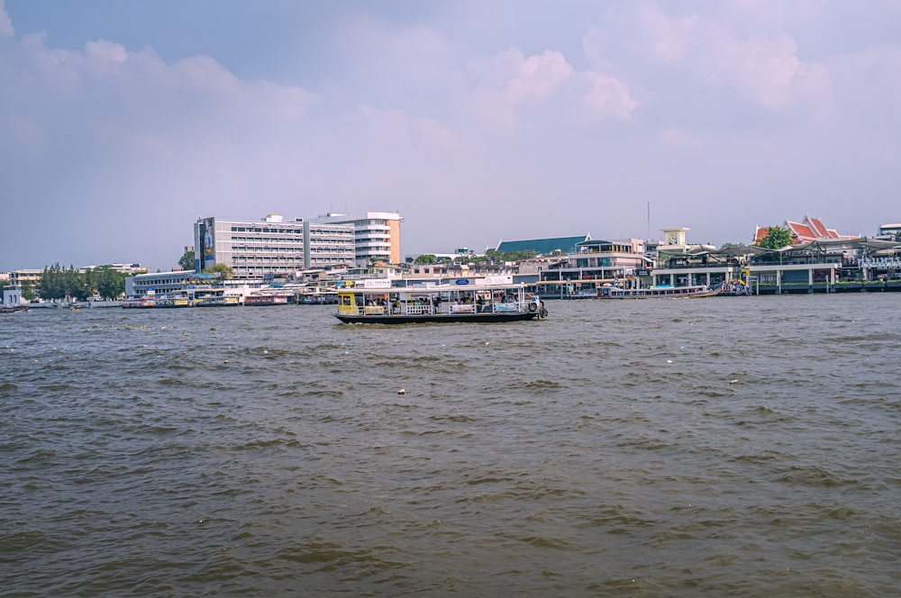 white and blue boat on sea near city buildings under blue sky during daytime