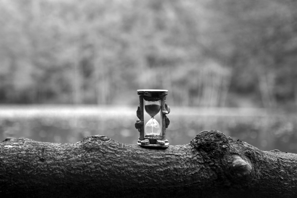 grayscale photo of hour glass on rock