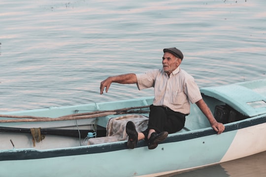 man in white dress shirt and black pants sitting on white and brown boat during daytime in Gölyazı Turkey