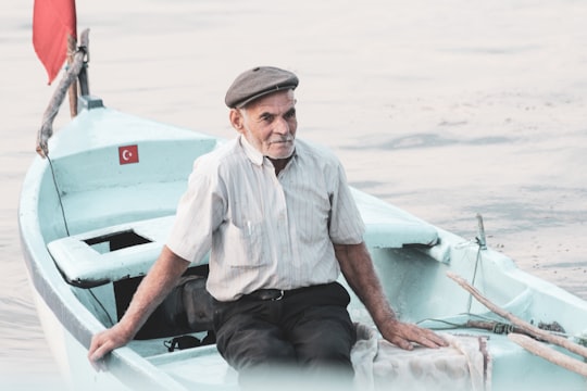 man in white button up shirt sitting on white boat during daytime in Gölyazı Turkey