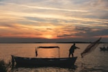 Fisherman silhouetted against a glowing orange sunset over calm Sri Lankan waters.