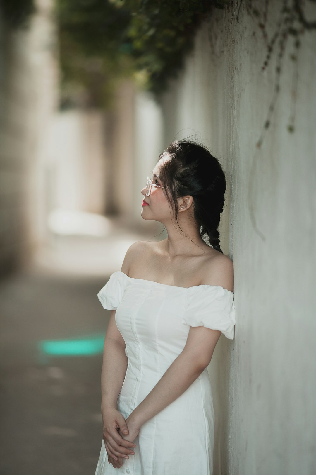 woman in white off shoulder dress leaning on wall
