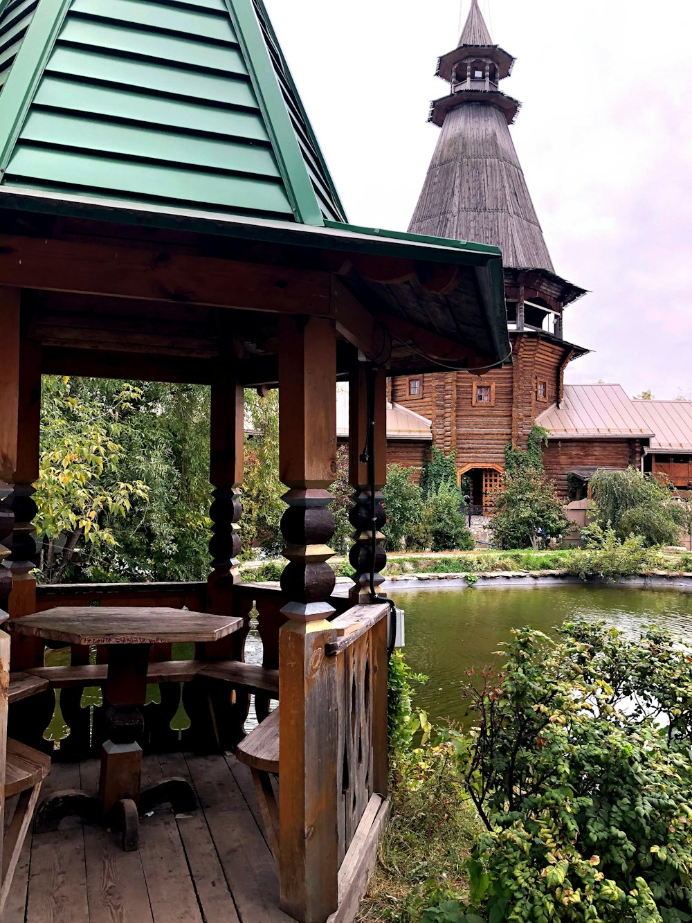 gazebo di legno marrone vicino agli alberi verdi e al fiume durante il giorno