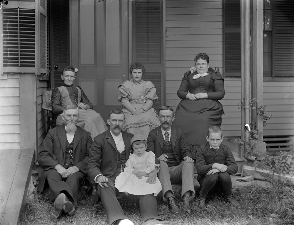 grayscale photo of 4 men sitting on grass field