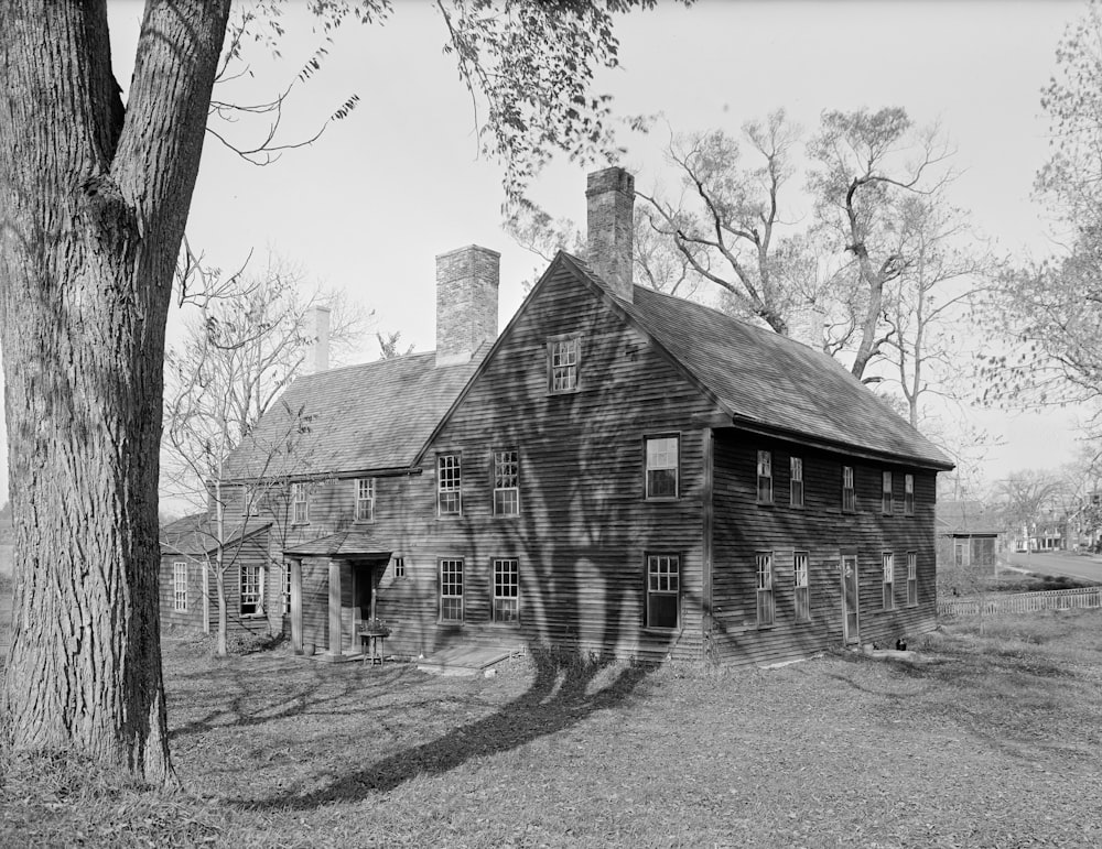 grayscale photo of wooden house near trees