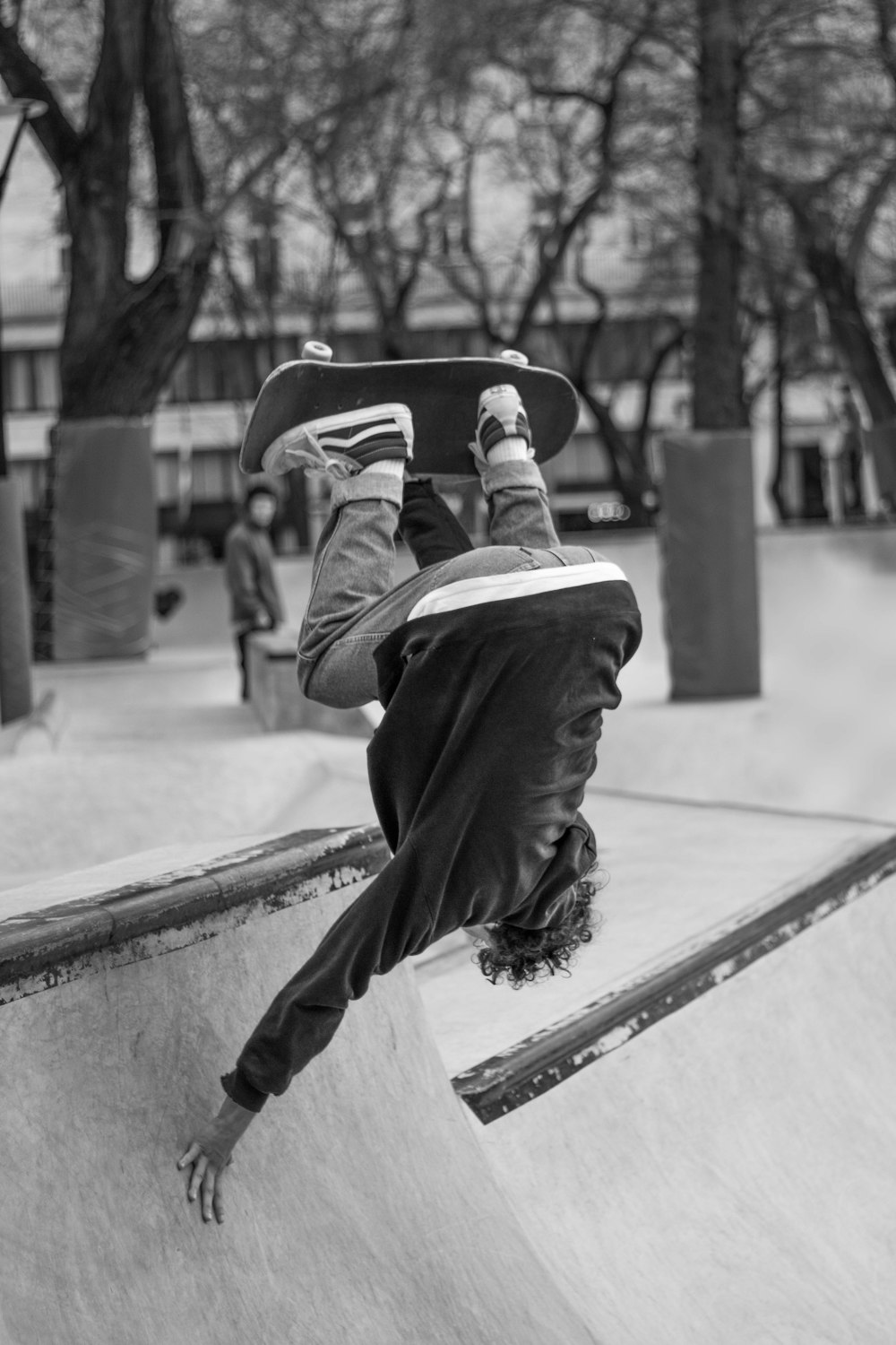 homme en veste et pantalon noir assis sur un banc en béton