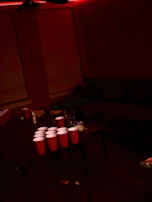 Close-up of a beerpong table showing balls mid-air towards red cups.