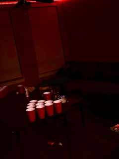 Close-up of a beerpong table showing balls mid-air towards red cups.