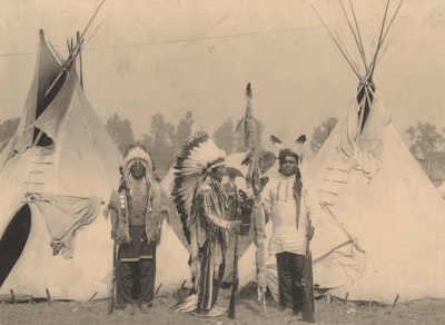 3 men in white and black coat standing on snow covered ground native american teams background