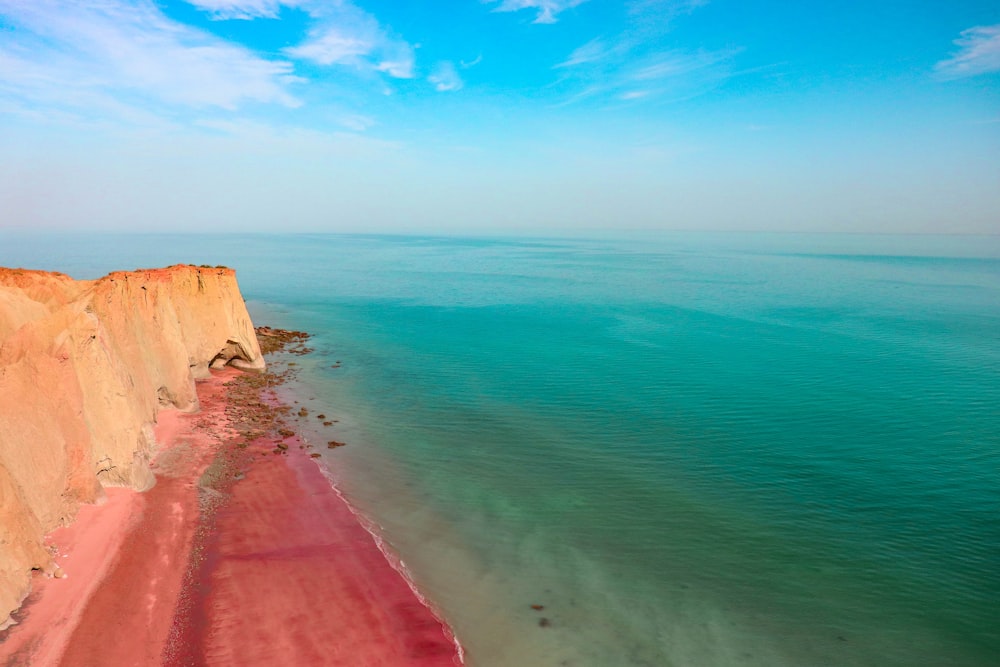 brown sand beside body of water during daytime