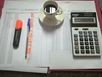 A cozy workspace with a laptop, notebooks, and a cup of coffee, surrounded by financial books and notes.