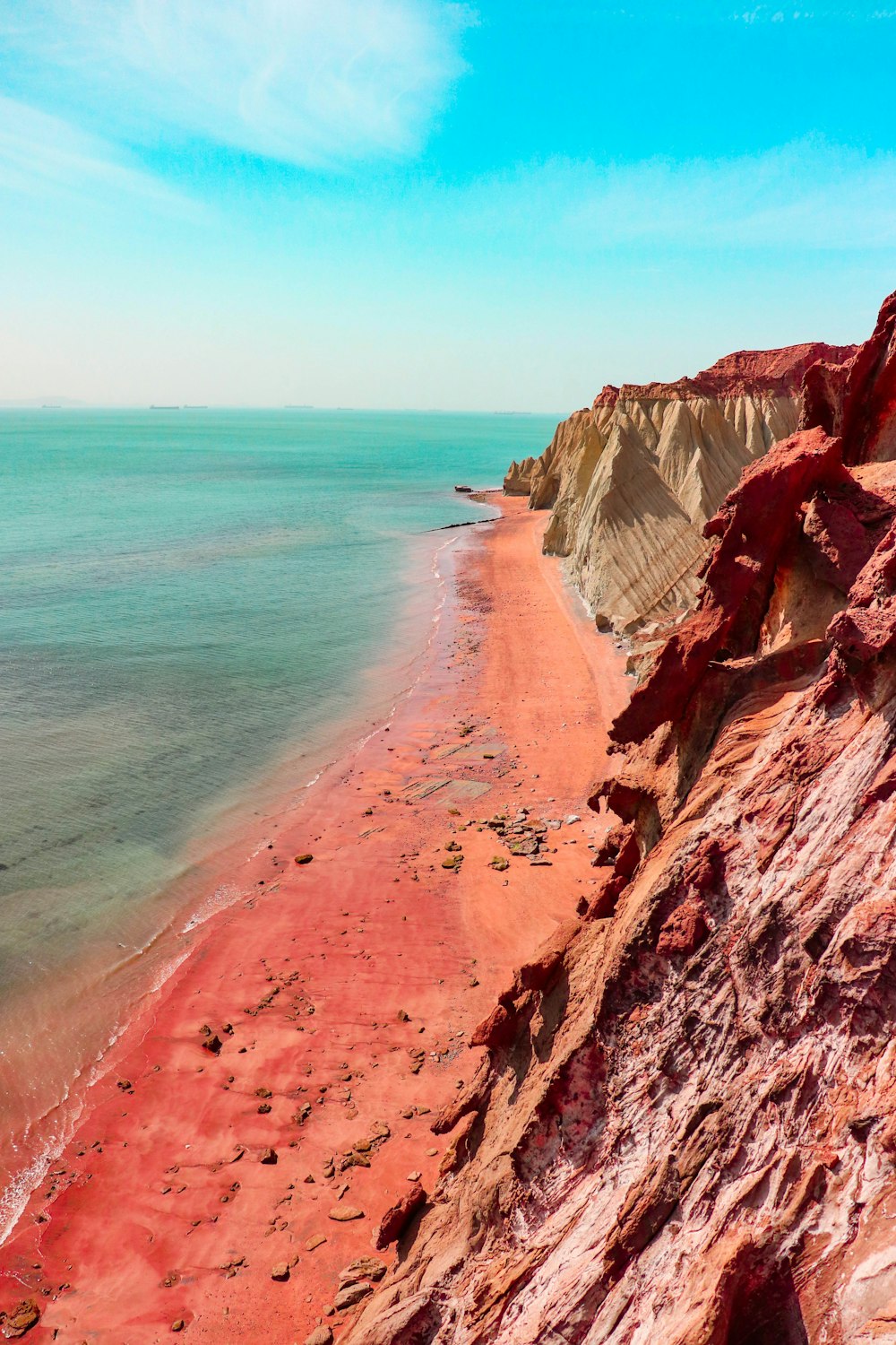 brown rocky mountain beside blue sea during daytime