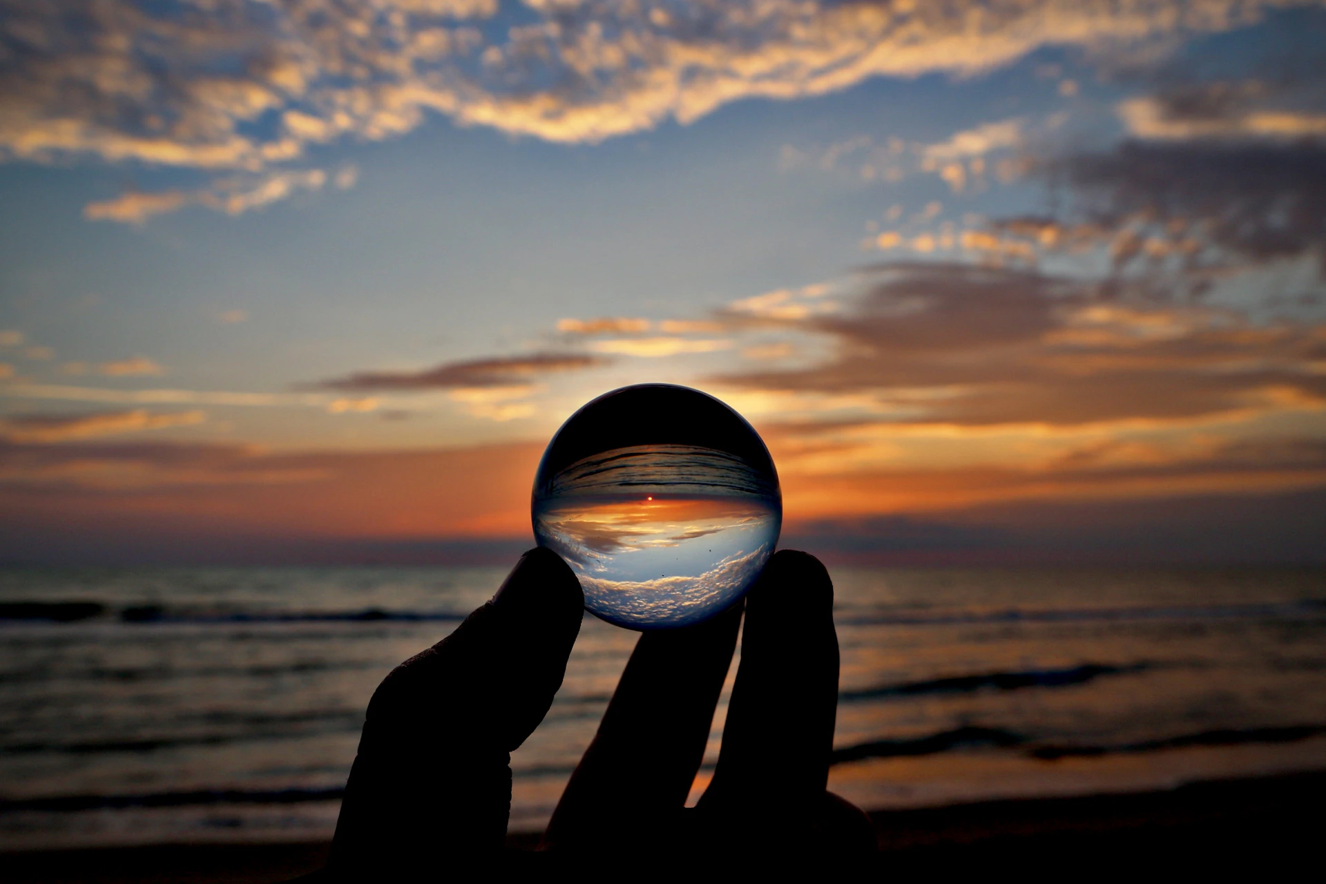 silhouette of person holding clear glass ball during sunset
