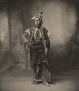 Portrait of a shaman in traditional attire against a dark background.