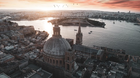 brown and white dome building near body of water during daytime in Valletta Malta