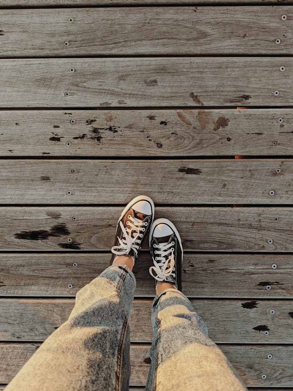 person in blue denim jeans and black and white sneakers