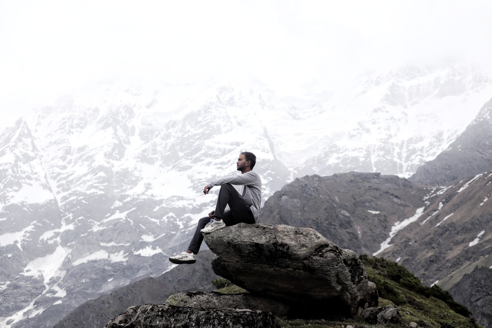 man in black jacket sitting on rock during daytime