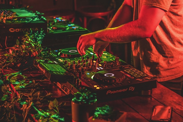 DJ mixing tracks on professional equipment surrounded by lively party guests.