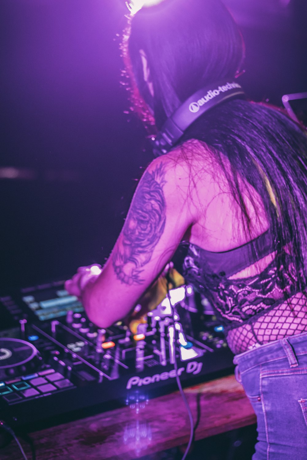 Frau in schwarz-weiß kariertem Hemd spielt DJ Mixer