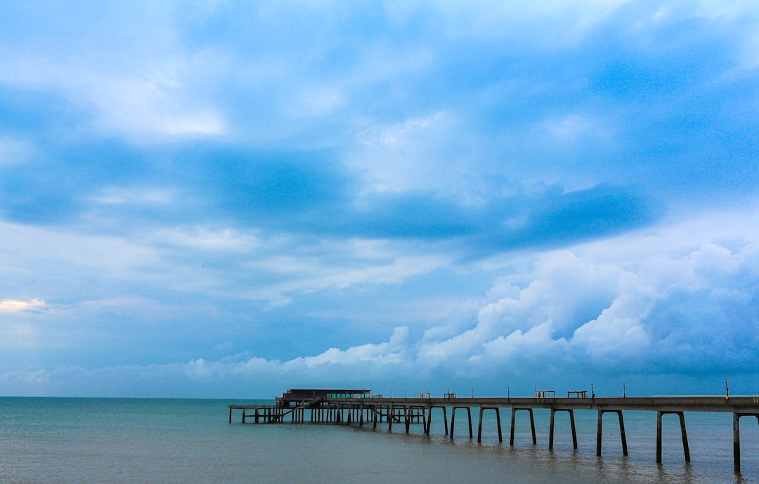 brown wooden dock on sea under blue sky and white clouds during daytime