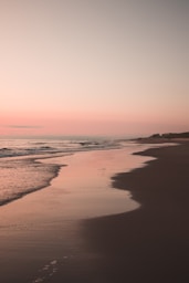 ocean waves crashing on shore during sunset