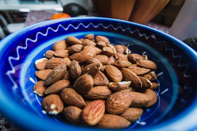 Close-up of glossy almonds and cashews in a rustic wooden bowl