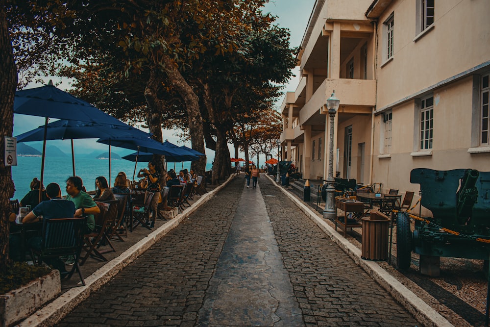 people sitting on bench under blue umbrella during daytime