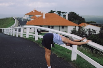 person in blue and white striped shirt and black shorts standing on gray asphalt road during