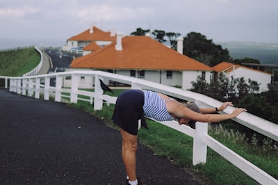 person in blue and white striped shirt and black shorts standing on gray asphalt road during